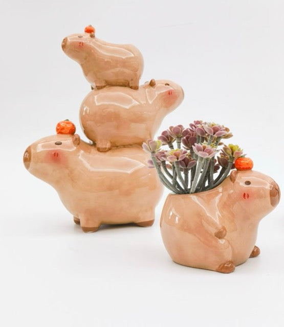 Set of three ceramic capybara-shaped planters with a small succulent plant on a white background
