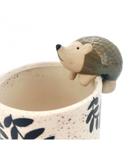 hedgehog shapred ceramic figure, perched on the lip of a planter