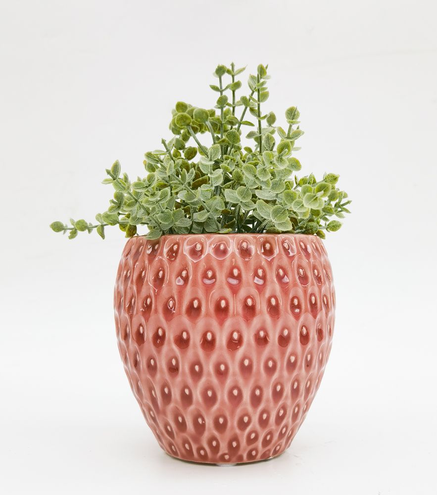 Pink textured, strawberry-shaped pot with green plant on a white background