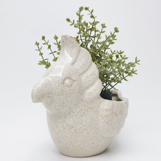 Ceramic galah-shaped planter with greenery on a light gray background