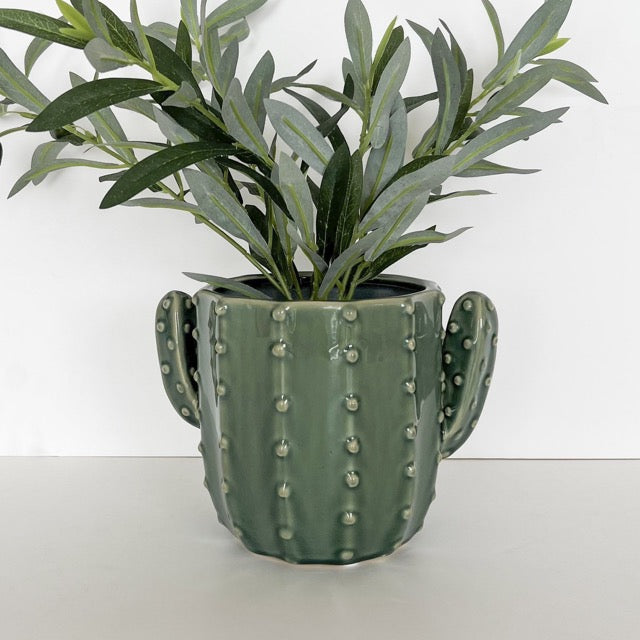Green cactus-shaped pot with a plant on a white background