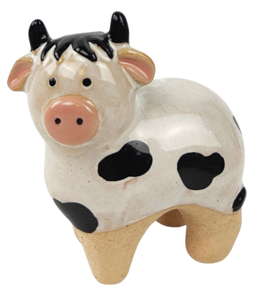 Ceramic cow figurine with black spots on that sits on the edge of a plant pot