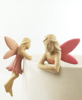 Two fairy figurines with pink wings and dresses that hang on the edge of your pot plant