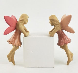 Two fairy figurines with pink wings and dresses that hang on the edge of your pot plant