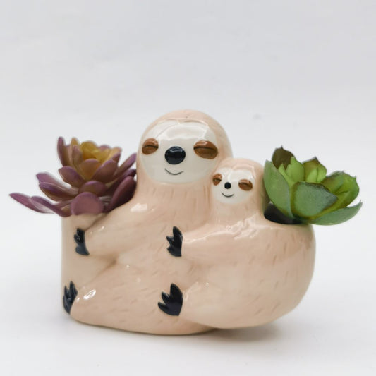 A ceramic planter featuring a design of two sloths hugging, with plants inside.