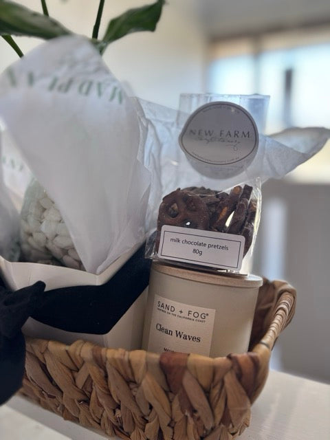 Basket with products including a bag of 'New Farm' chocolate pretzels and a candle