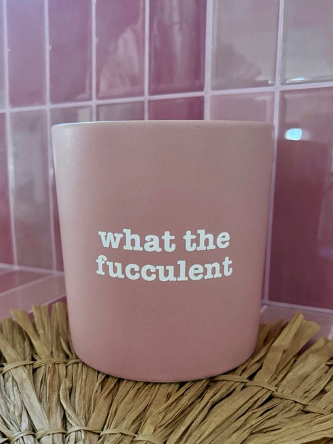 Pink mug with white text 'what the fucculent' on a textured surface with tiled wall background