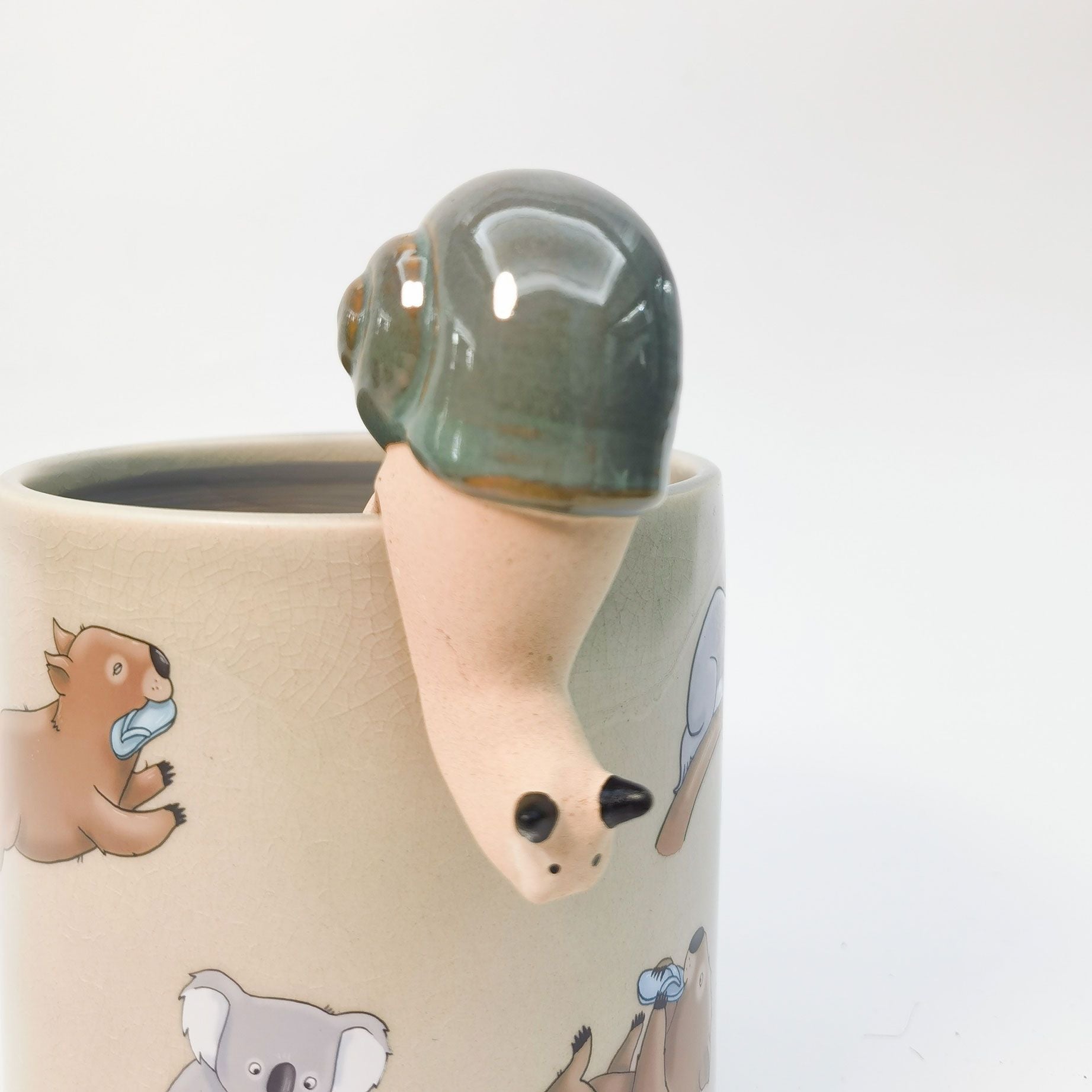 Ceramic snail sitting on the lip of a plant pot