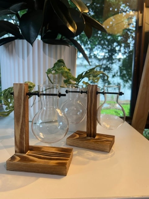 timber stand with glass jar hanging on black metal rod. for plant cuttings or flowers