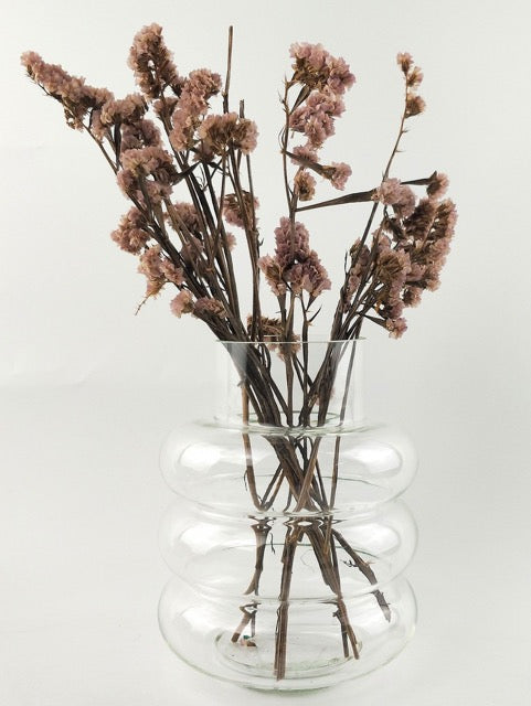 Clear glass vase with dried pink flowers on a white background