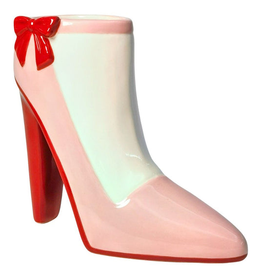 Pink high-heeled shoe vase  with a red bow on a white background