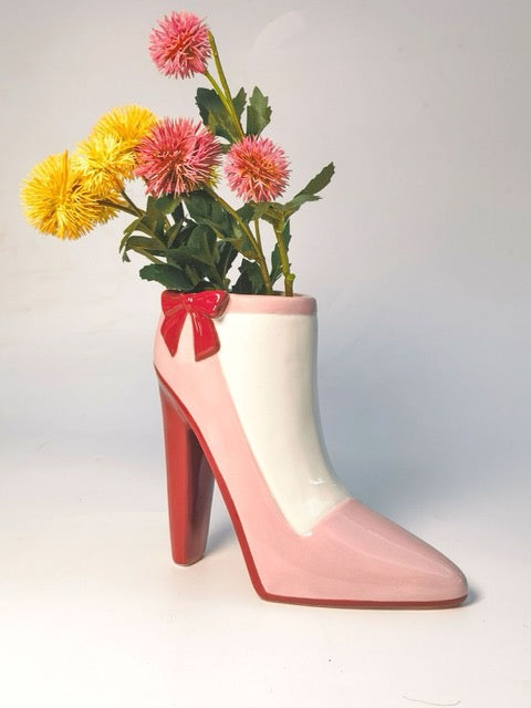 Pink high-heeled shoe vase with flowers on a white background