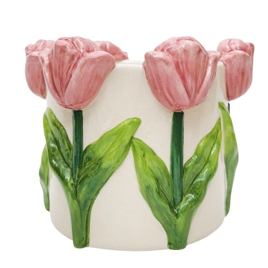 Ceramic vase with pink tulips and green leaves on a white background