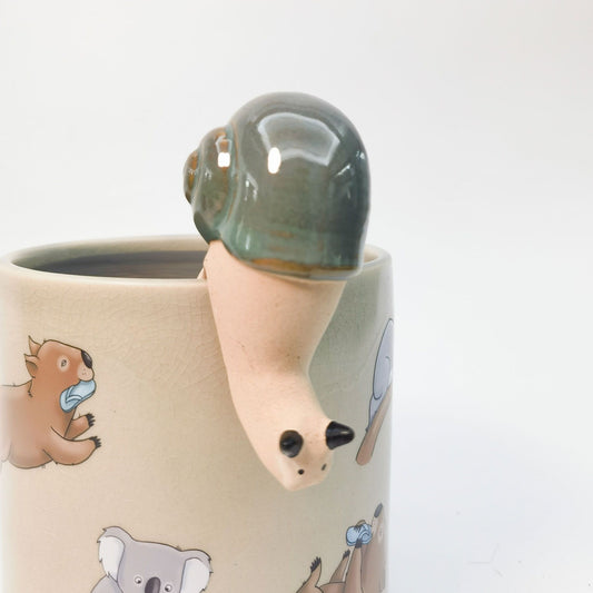 Ceramic snail sitting on the lip of a plant pot